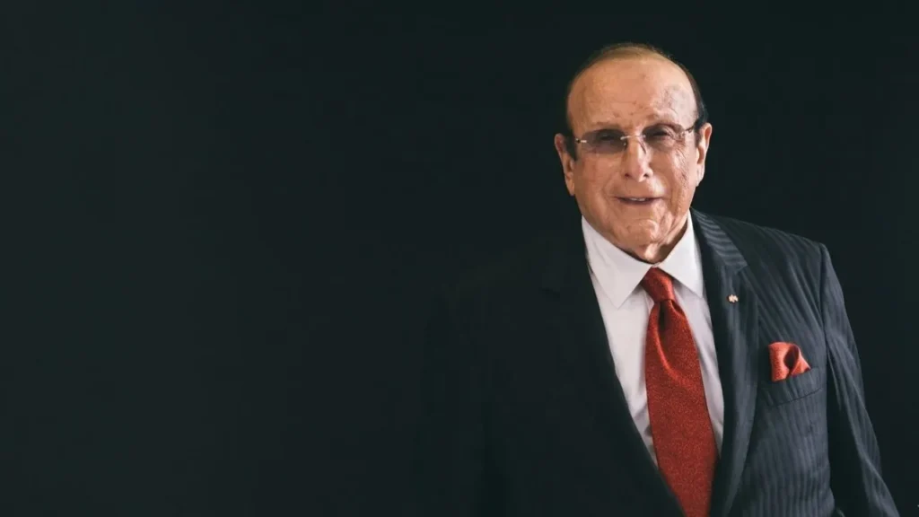 Iconic music executive Clive Davis smiling warmly in a sharp tailored suit at a luxury industry gala.