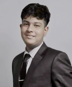 Portrait of Adarsha Dhakal, founder and editor of Investozora, wearing a dark suit and tie against a light gray background.